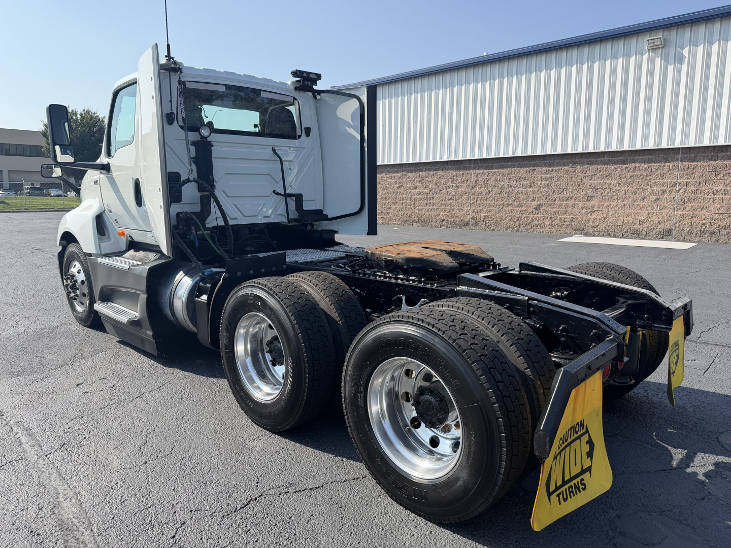 Truck chassis side view showing dual rear axles and cab of a 2022 International LT625 with open rear deck and mud flaps.