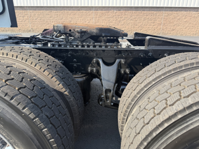 Truck rear drivetrain showing dual rear axles and fifth wheel area, with visible leaf springs, suspension, and frame members.