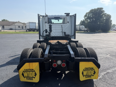 Truck rear view showing fifth wheel and dual rear axles, with yellow wide-turn caution signs on both sides.