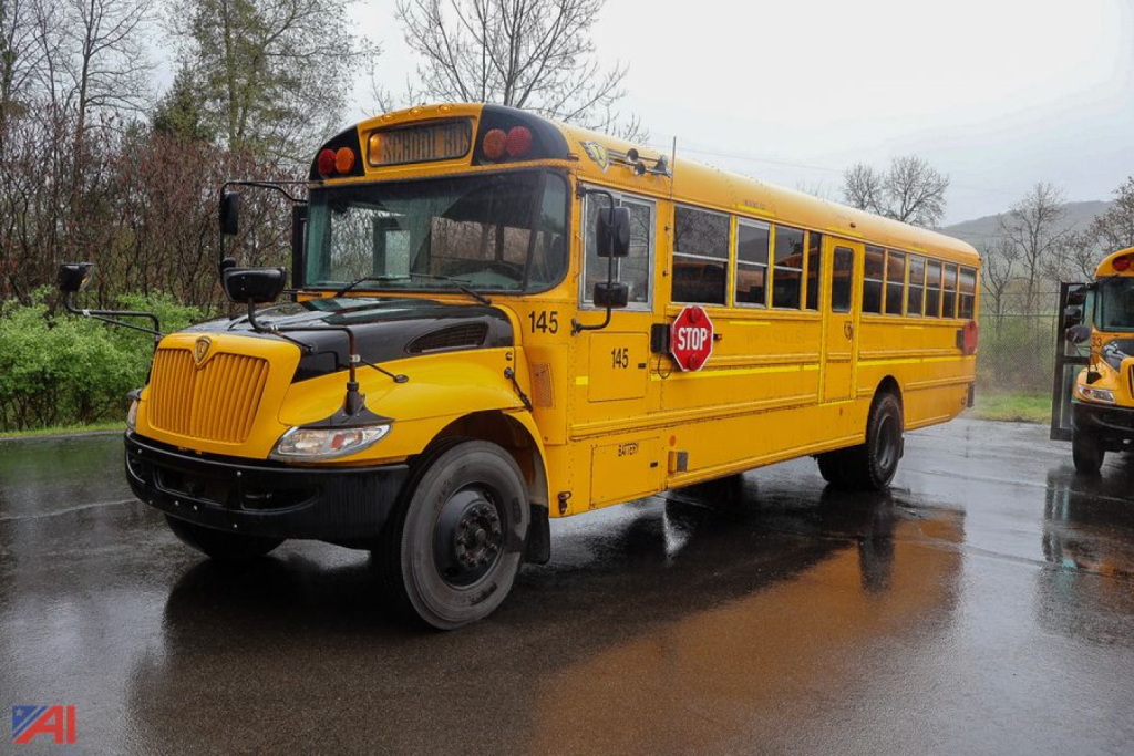 IC Corporation CE Series school bus in yellow, side view with stop sign, 145 fleet number, front grille and dark bumper, wet pavement.