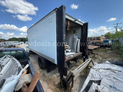 Box truck cargo area with rear doors open showing interior with stacked materials and ramp, International 4400 yard scene.
