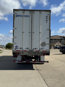 Rear view of a Utility 4000D-X trailer showing closed double doors, VIN and stock number on the back, with a River Valley logo and taillights.