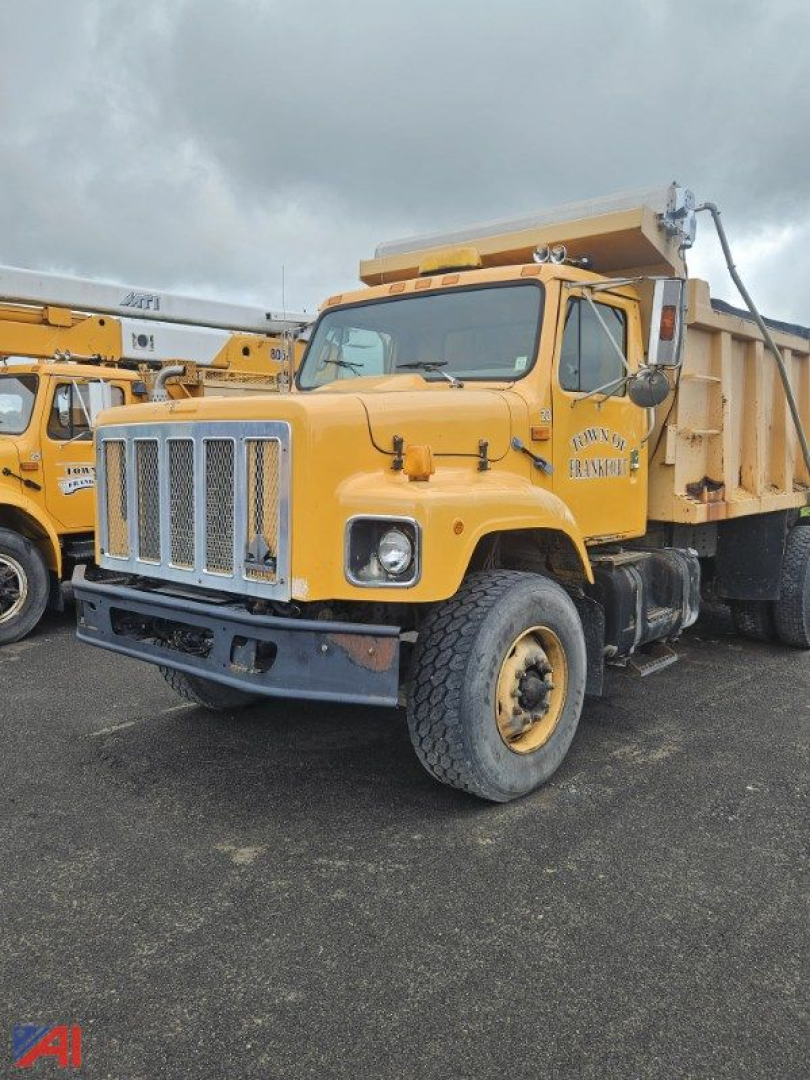Dump truck in-service 2000 International 2674 dump truck with yellow body and black bumper, large chrome grille, dump bed, side exhaust, and dual rear wheels.