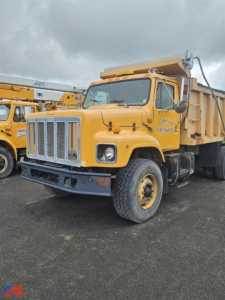 Dump truck in-service 2000 International 2674 dump truck with yellow body and black bumper, large chrome grille, dump bed, side exhaust, and dual rear wheels.