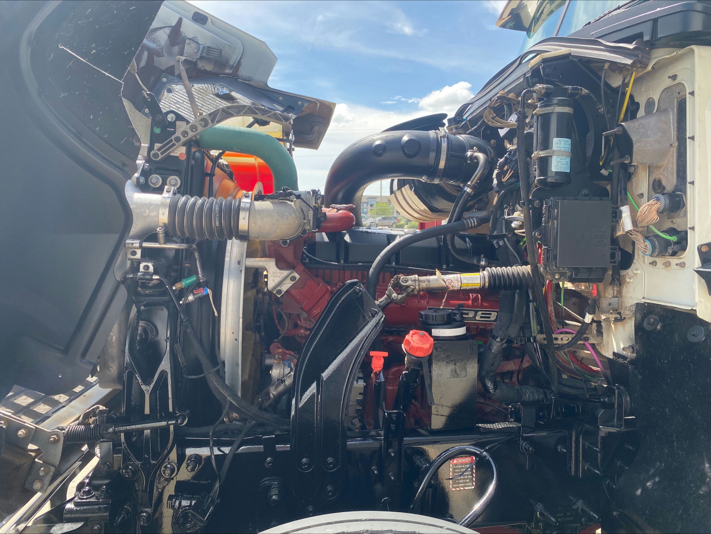 Mack PI64T engine bay with visible hoses, coolant reservoir, and various components; no legible-labels or serials readable clearly in the image.