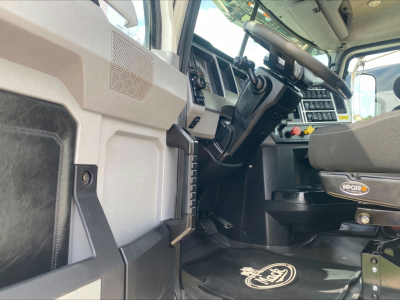 Cab interior of a 2021 Mack PI64T showing steering wheel, dashboard, and driver's footwell with Seabo sticker; visible components include pedals and control panels.