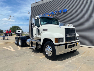 2021 Mack PI64T conventional daycab truck in white, front three-quarter view, parked outside dealership with 'TRUCK CENTER' sign in background.