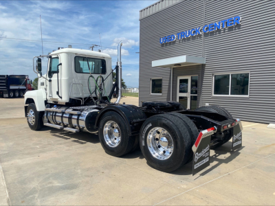 Mack PI64T tractor at used truck center showing cab and dual rear axles with chrome wheels.