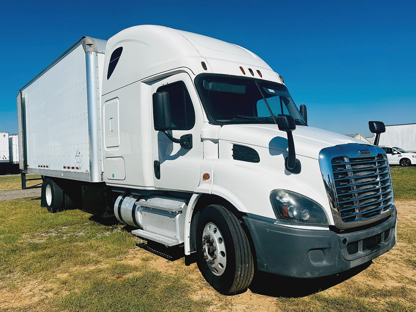 1995 Freightliner Cascadia113 truck in white with a large box trailer, side view showing cab and front grille, no visible text on image.