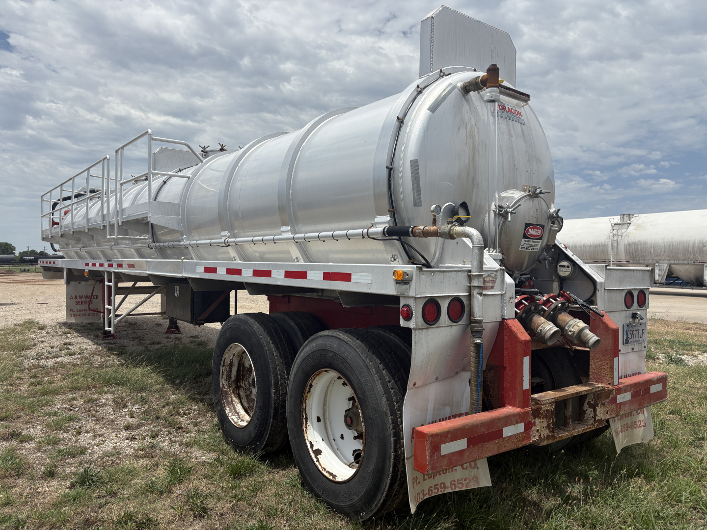 Semi-trailer vacuum tanker in side and rear view showing cylindrical stainless steel tank with rear coupler and dual axle wheels.