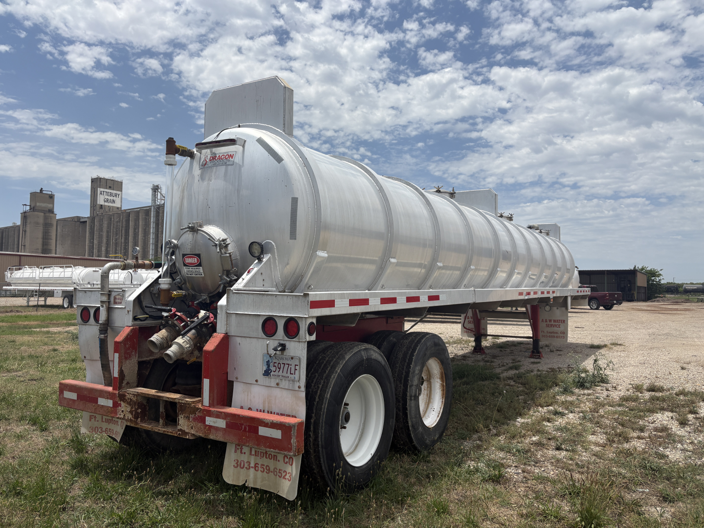 Rear/side view of a 2012 Dragon 150BBL Vacuum trailer with cylindrical stainless steel tank, dual rear axles, and mud flaps; VIN placard and stock number visible.
