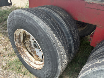 Trailer dual rear tires with visible wear showing wheel rims, part of a red vacuum trailer body.
