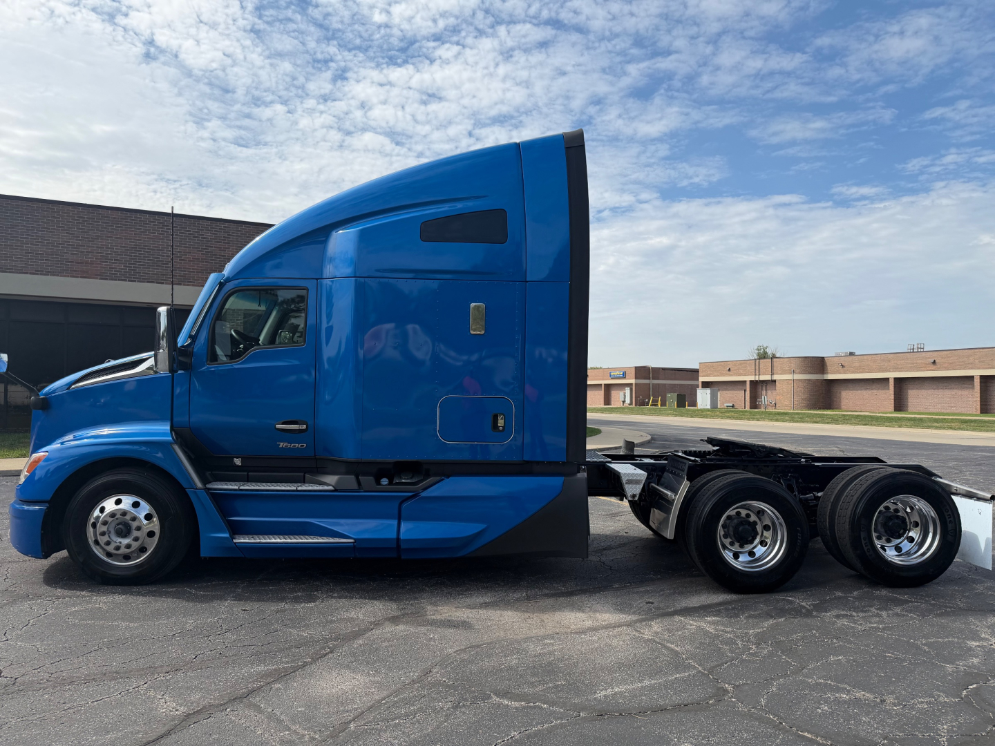 Kenworth T680 tractor unit side view showing blue sleeper cab and extendable chassis with three rear axles.