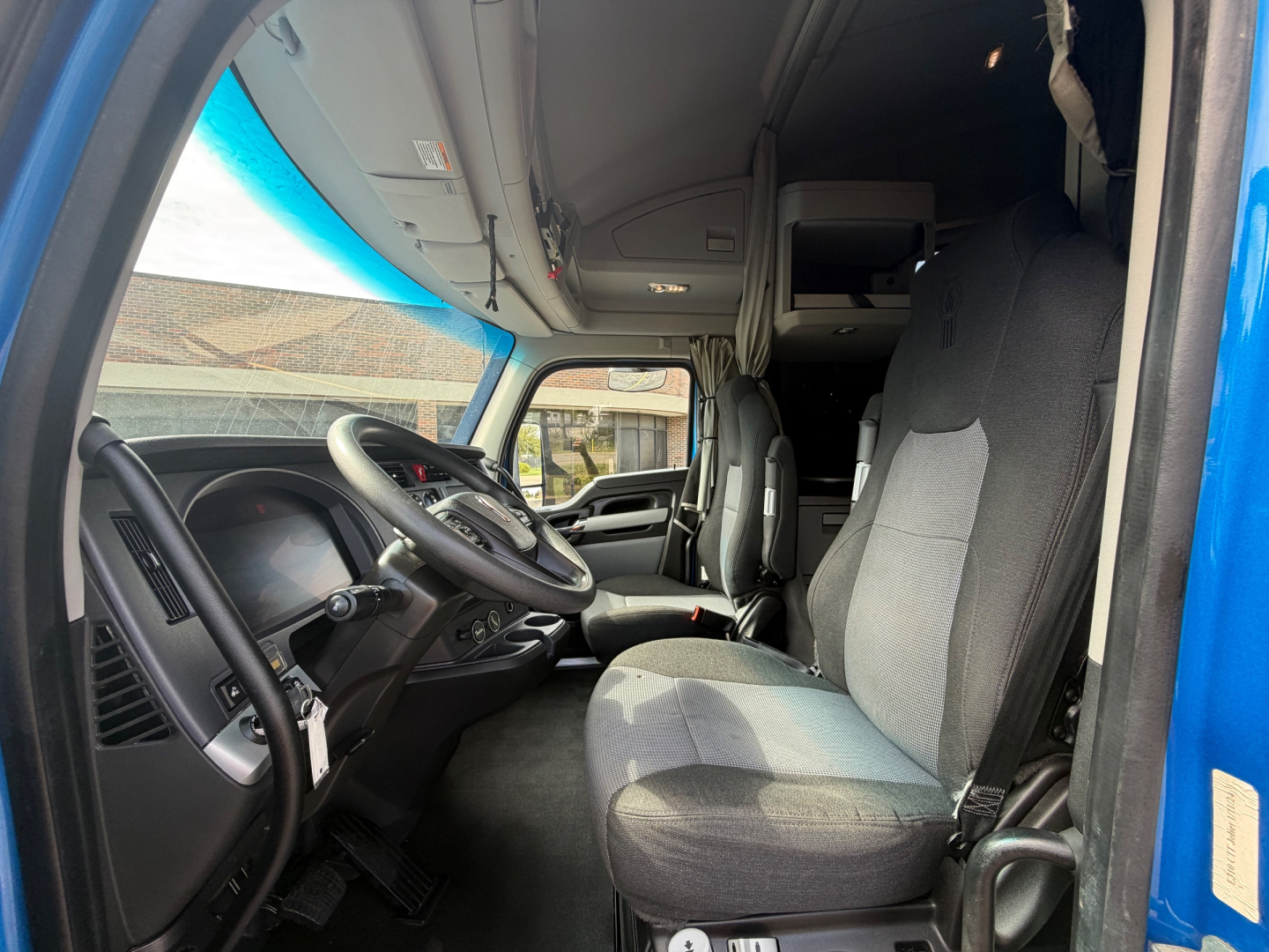 Kenworth T680 truck cab interior showing driver seat and dashboard with steering wheel and controls.