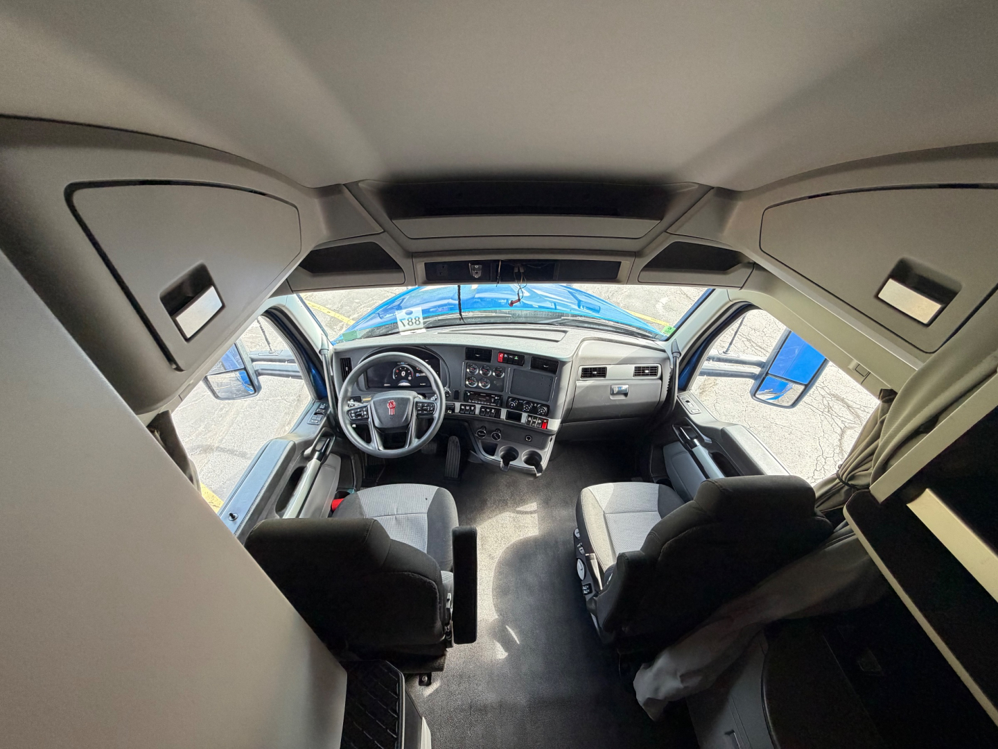 Kenworth T680 truck interior view from cab showing steering wheel, dashboard, and front seats.