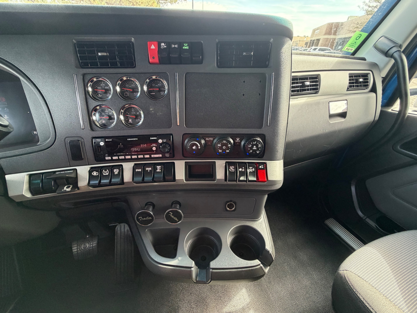 Dashboard of 2023 Kenworth T680 interior showing instrument cluster, climate controls, and center console with cup holders.