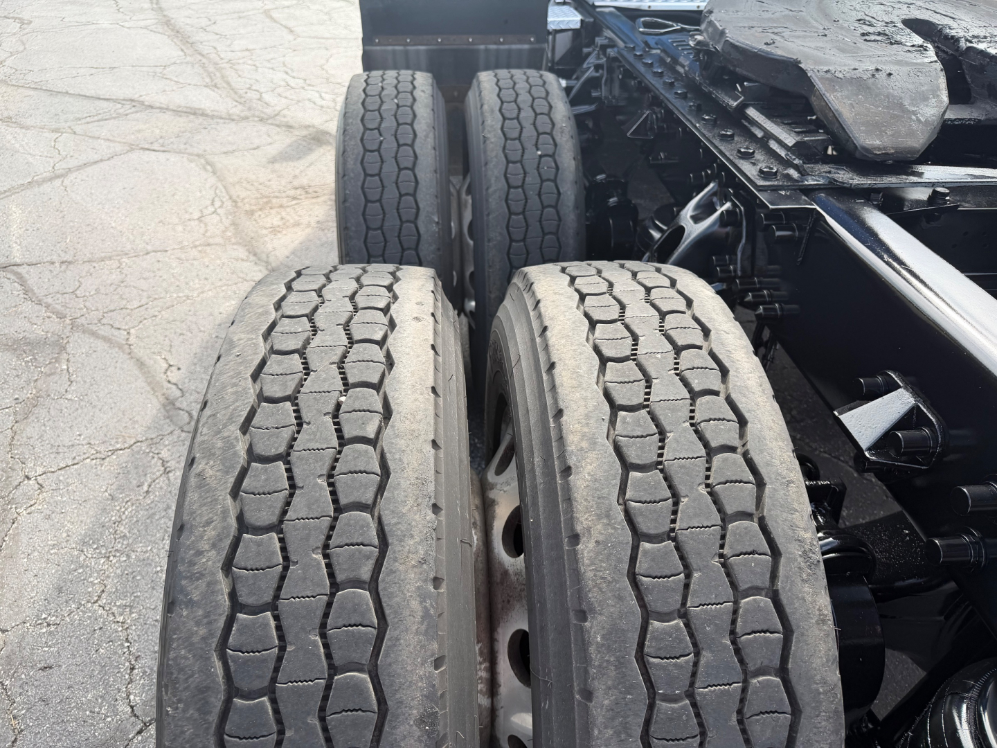 Kenworth T680 rear wheel area showing dual rear axles and treaded tires and chassis frame