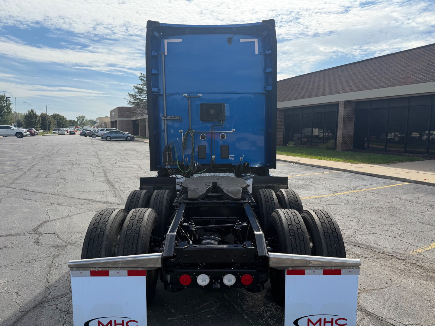 Kenworth T680 truck rear view showing fifth wheel and dual rear axles, blue cab, and black chassis with mud flaps and lights.