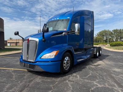 Kenworth T680 blue sleeper cab truck in a parking lot, front three-quarter view.