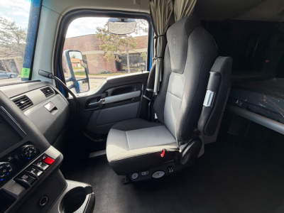 Kenworth T680 truck cab interior showing driver's seat and dashboard with gray fabric seats and control panel.