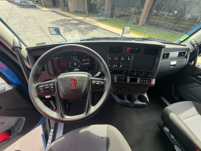 Dashboard and steering wheel of a 2023 Kenworth T680 truck interior showing steering wheel, gauges, center console, and driver seat.