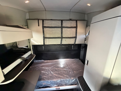 Kenworth T680 sleeper cab interior with bunk bed area and storage compartments visible.