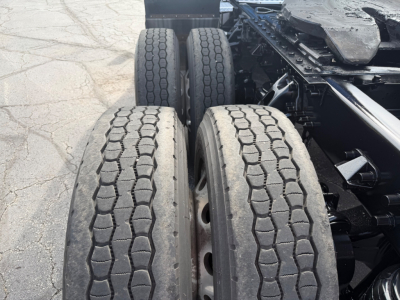 Kenworth T680 rear wheel area showing dual rear axles and treaded tires and chassis frame