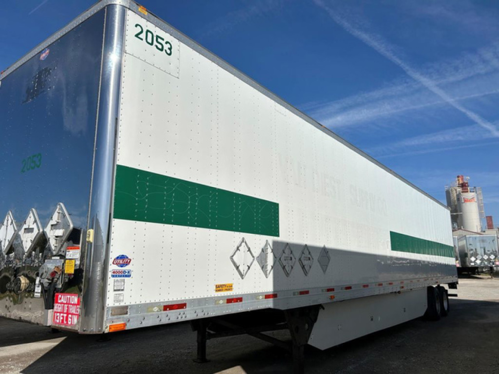 Trailer side view showing 2016 utility van dry van trailer with green bands and safety decals, VIN plate not visible.