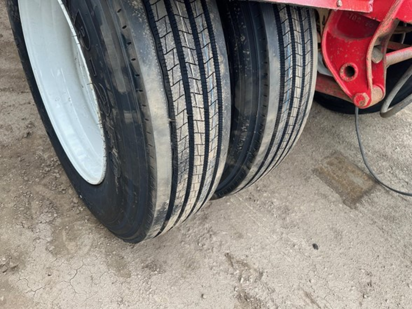 Quad trailer wheel assembly with multiple tires and red frame, visible tread details.
