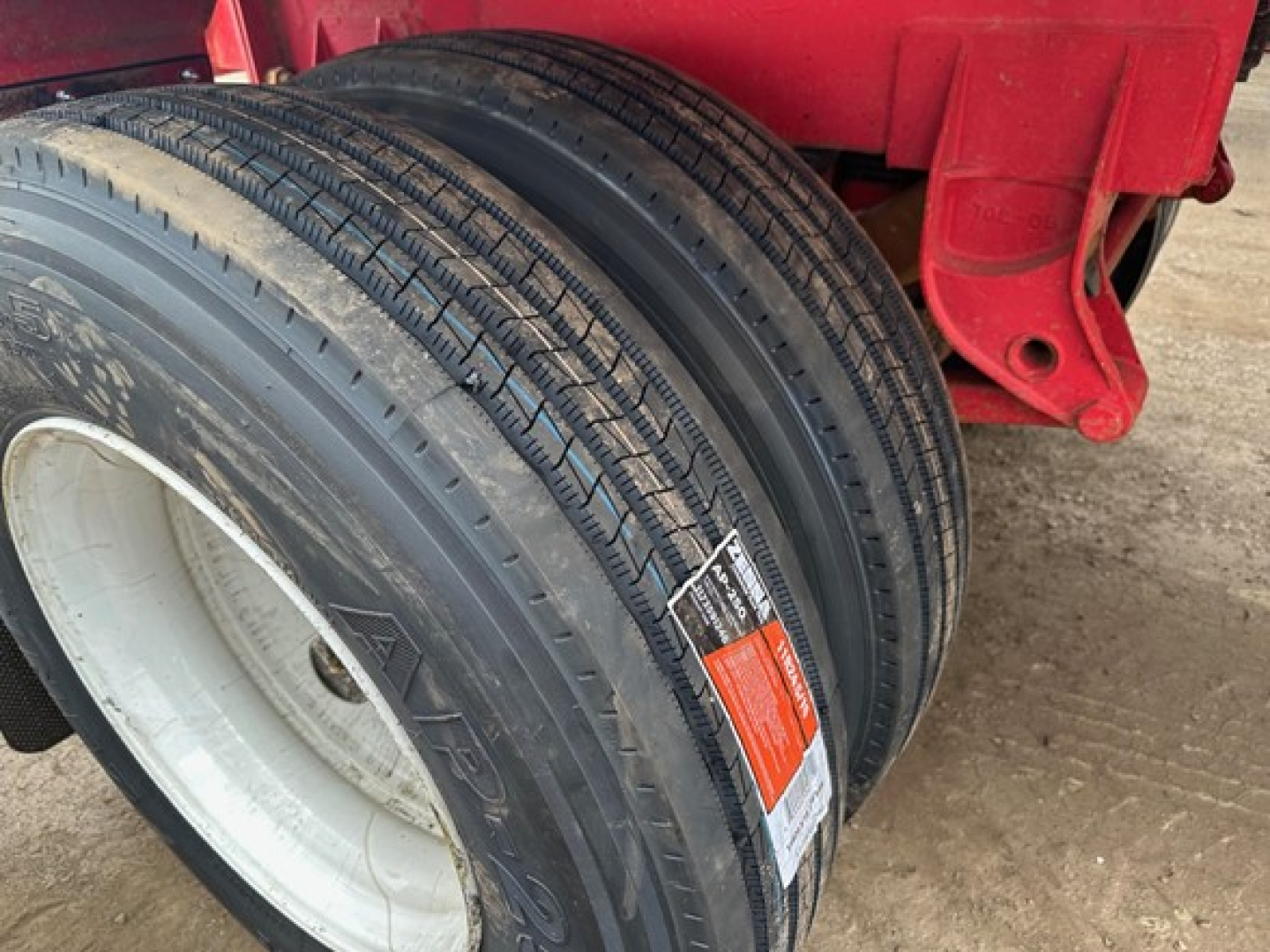 Trailer wheel and dual tires showing Ranco LW11-20P label on side; red trailer frame; white wheel rim; tread details visible.