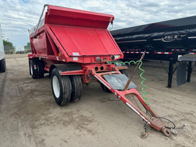 Dump trailer showing rear dump bed and hitch with red paint and dual rear axles; no visible branding text legible.