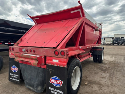 Dump trailer showing rear view of red Ranco LW11-20P with dual axles and tailgate raised, Utility logo mudflaps, parking lot with other trailers.