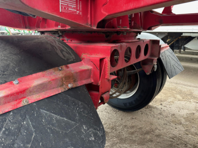 Ranco LW11-20P dump trailer wheel area showing red frame with circular cutouts and coil springs, partial tire and dirt ground.