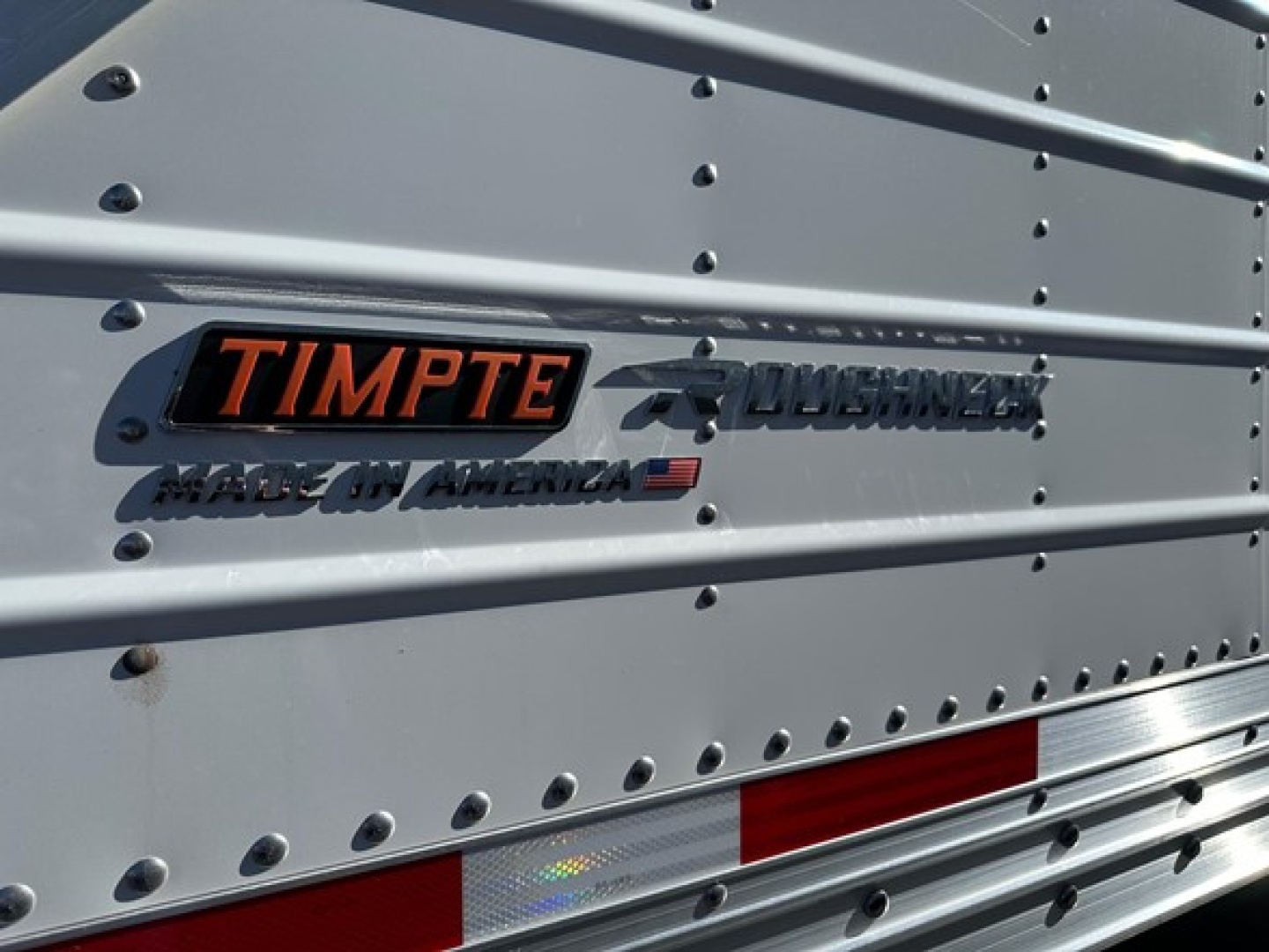 Timpté Roughneck hopper bottom trailer side panel showing TIMPTE badge and Roughneck logo with Made in America text.