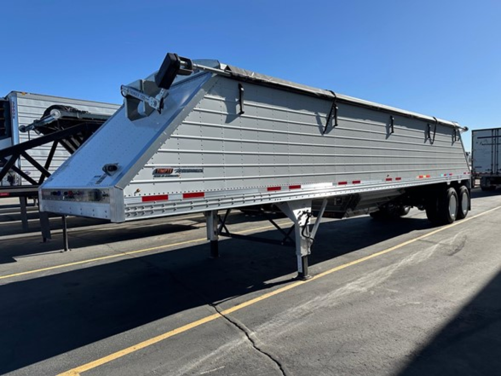 Timpte Roughneck hopper bottom trailer in a parking lot, side view showing dump chute and dual rear axles.