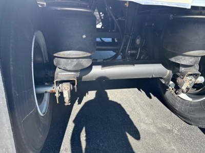 Rear view of a Timpte hopper trailer suspension and axle assembly with dual tires, leaf springs, and hub components visible under the trailer.