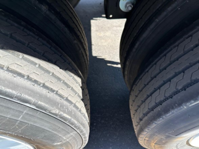 Trailer axle section with dual tires showing close-up of tire treads and wheel hubs