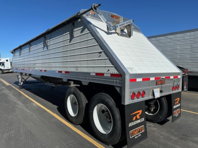 Trailer showing Timpte Roughneck hopper bottom tailer with alloy sides, rear tailgate open, dual rear axles, red and white reflective tape, NE11885 stock number visible on tail. 