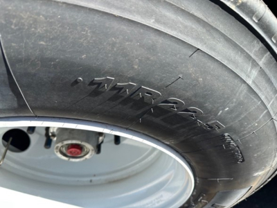 Tire close-up on a Timpte Roughneck hopper bottom trailer showing the word 'Roughneck' on the tire sidewall and a wheel hub in the background.