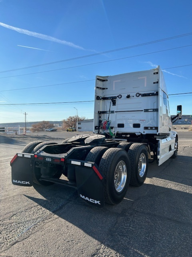 Truck cab rear and dual rear axles of a 2026 Mack PR64T64 conventional sleeper truck showing chassis, fifth-wheel area, and mud flaps with Mack branding.