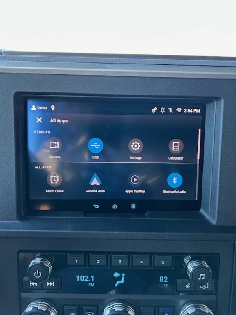 Dashboard area of a 2026 Mack PR64T64 showing a touchscreen infotainment display and climate/controls cluster with radio tuned to 102.1 FM.