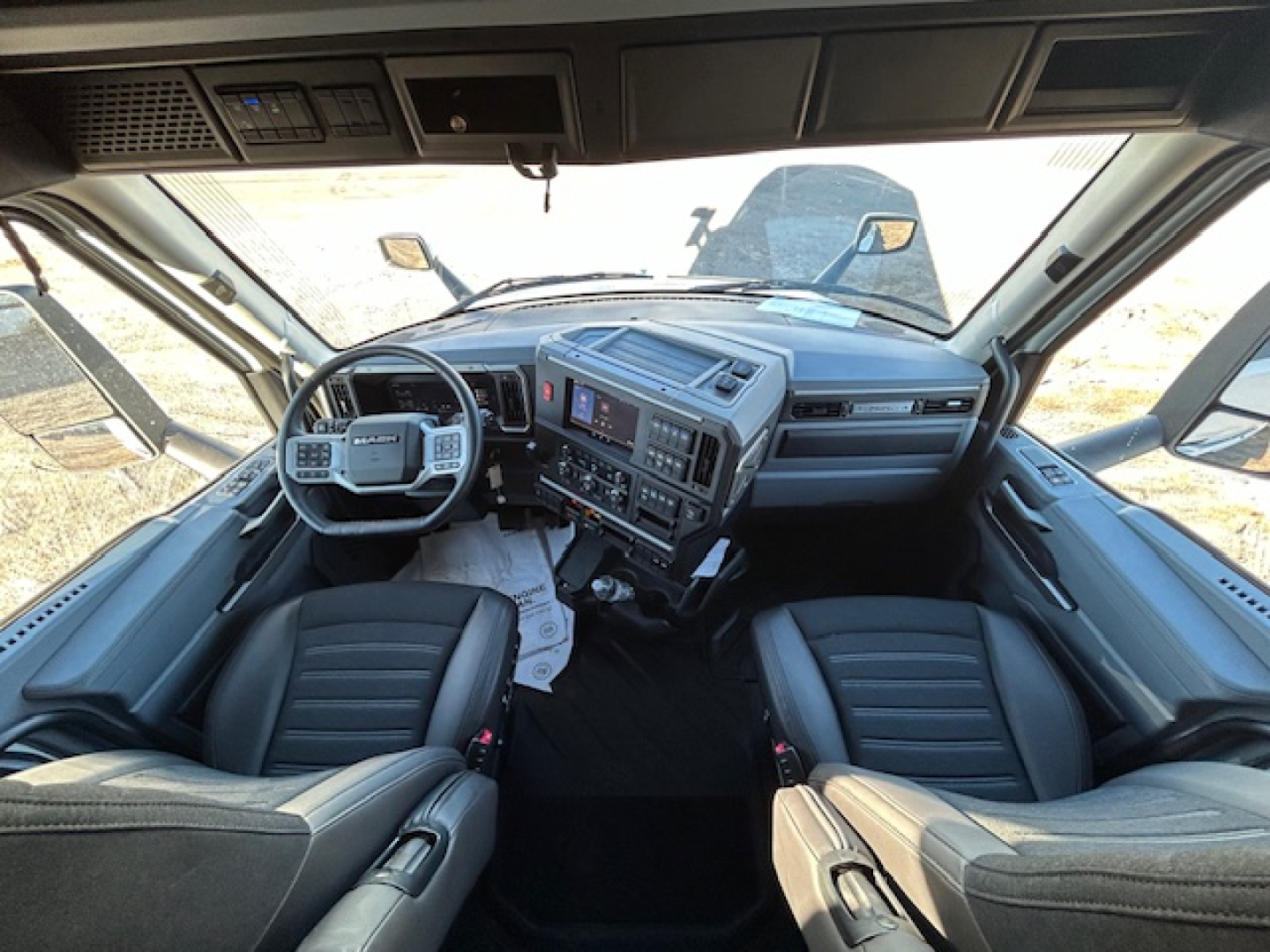 Cab interior of a 2026 Mack PR64T64 truck showing steering wheel, dashboard with digital display, center console, and two front seats.