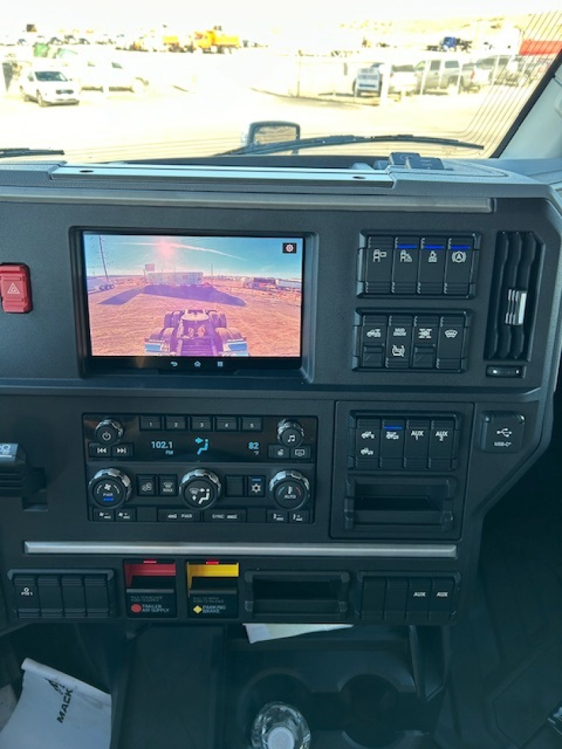 Truck dashboard of a 2026 Mack PR64T64 with a central touchscreen display and multiple control panels visible, including climate controls and switchbank.