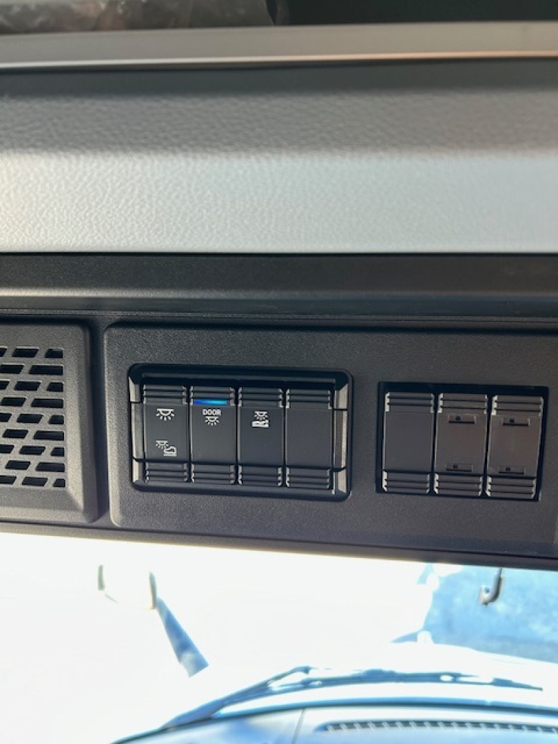 Dashboard controls of a Mack PR64T64 truck showing switch panel with HVAC/defrost settings and other toggle switches.