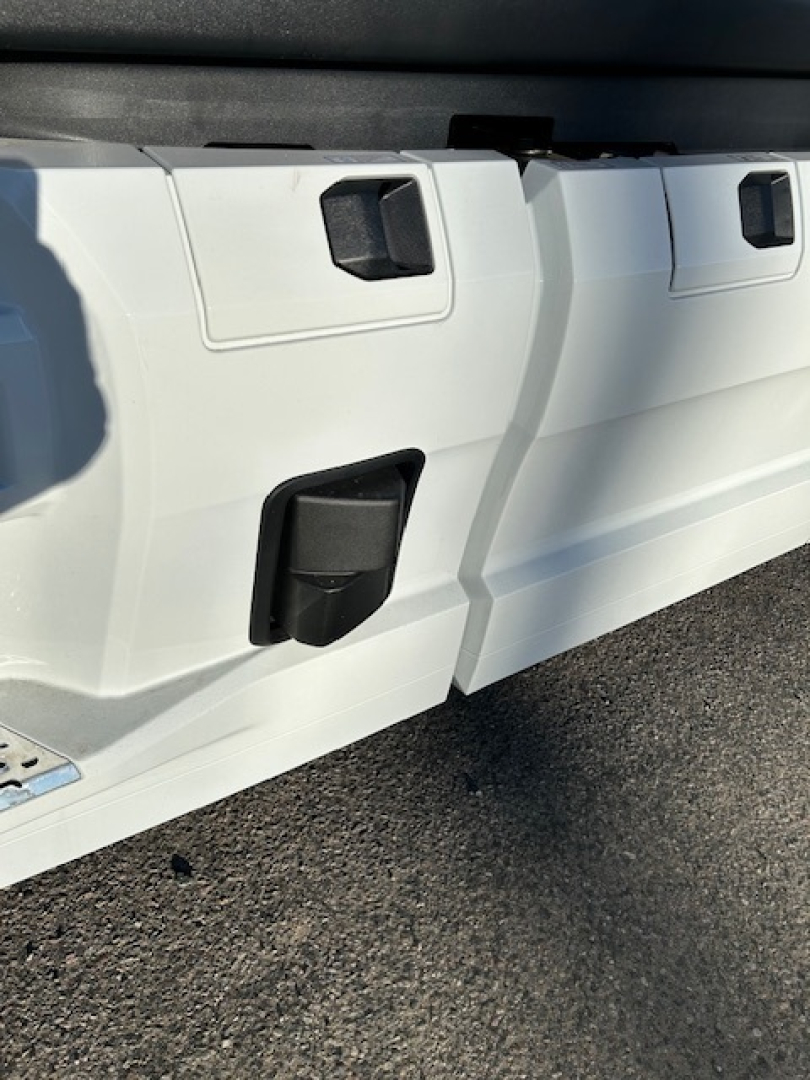 Tractor-trailer side panel showing utility access doors and black latches on a white Mack PR64T64 cab/chassis.