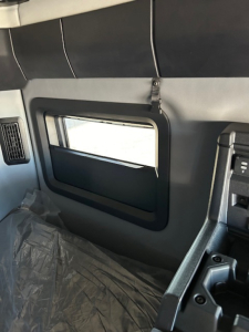 Truck cab interior with side window, door panel and controls visible.