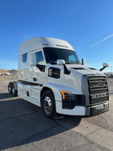 Truck cab exterior in a parking lot showing a white 2026 Mack PR64T64 with black grille and side mirrors.