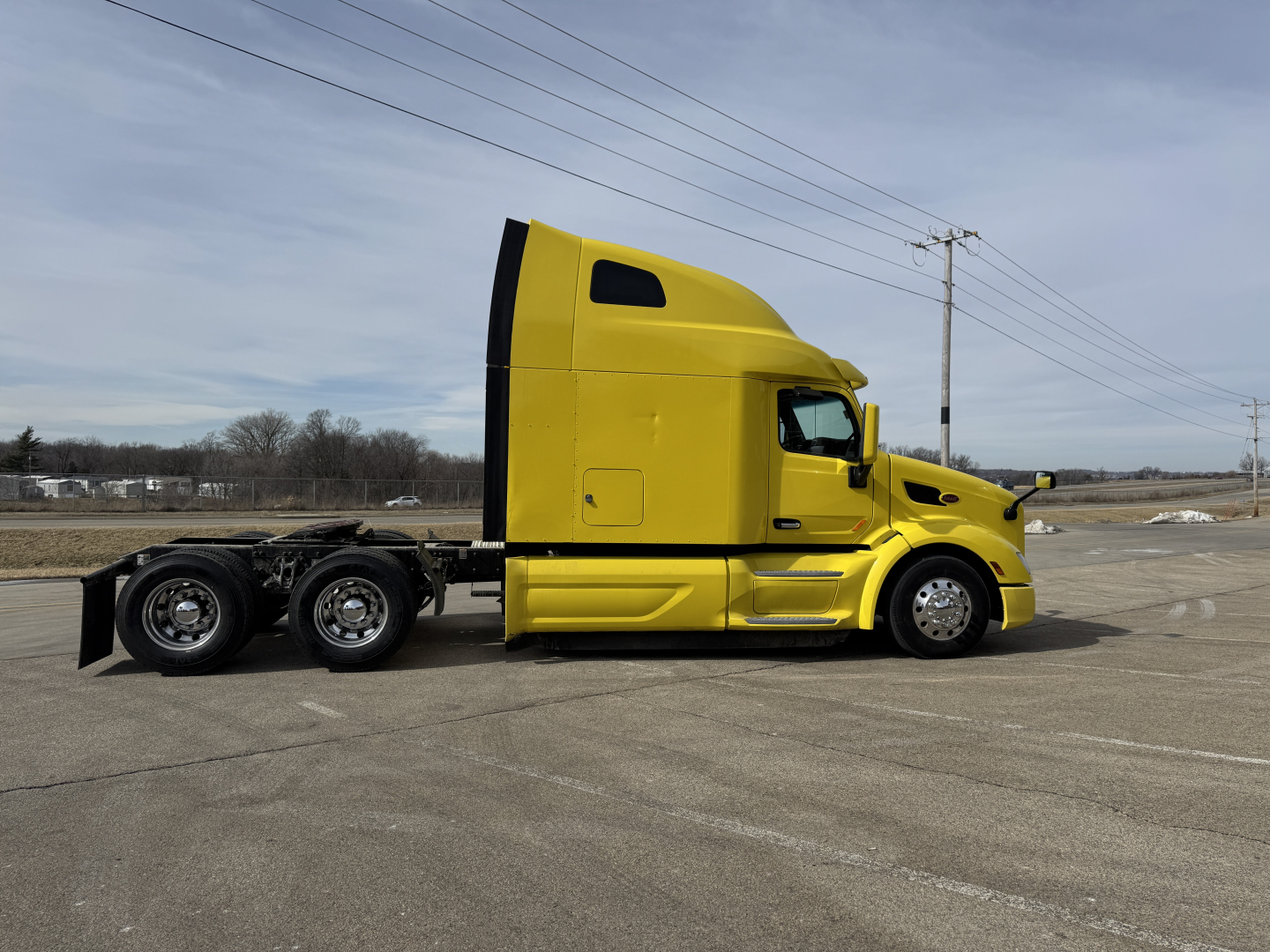 2020 Peterbilt 579 conventional sleeper tractor in yellow, side view showing cab and tandem rear axles.