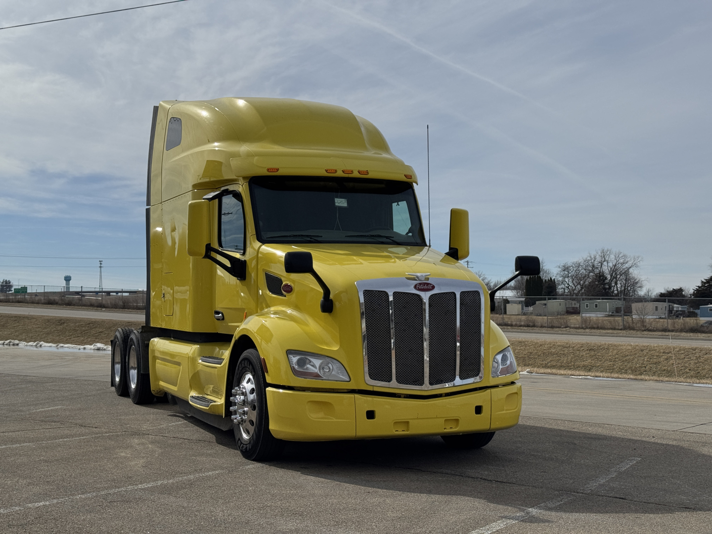 Peterbilt 579 tractor in yellow paint showing front grille and headlights.