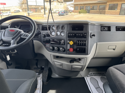 Truck cab interior of a 2020 Peterbilt 579 showing steering wheel, dashboard gauges, switches, and center console.